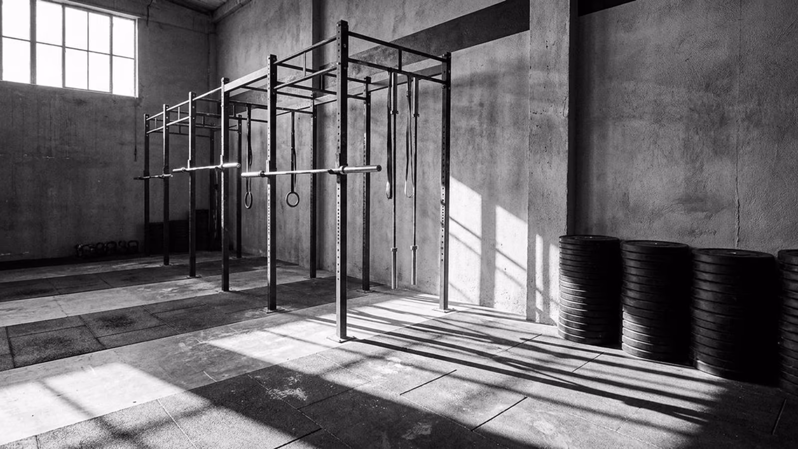 Rig central de CrossFit Atocha con barras olímpicas colgadas y una pared con discos ordenados por peso.